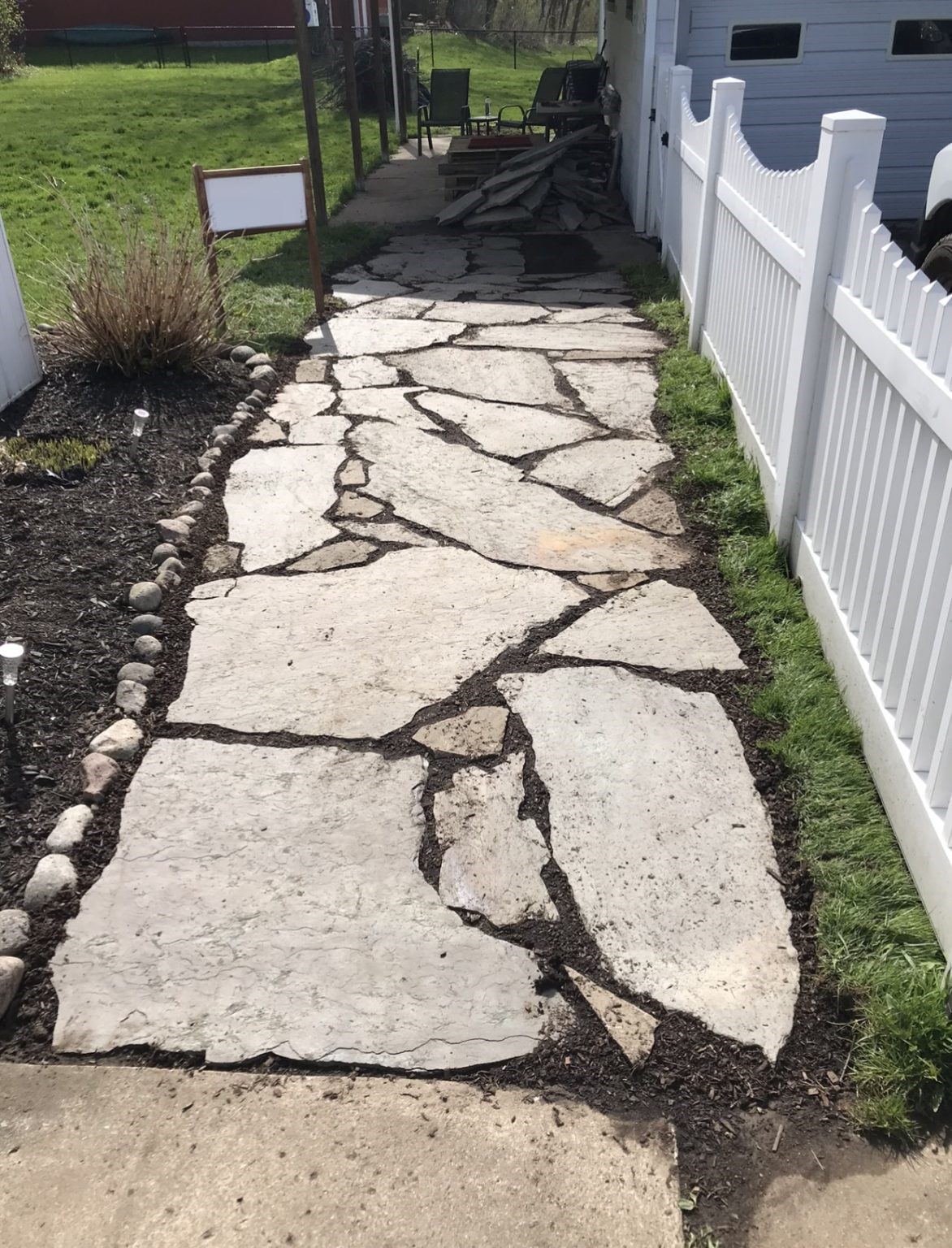 Custom flagstone walkway installed along a white fence